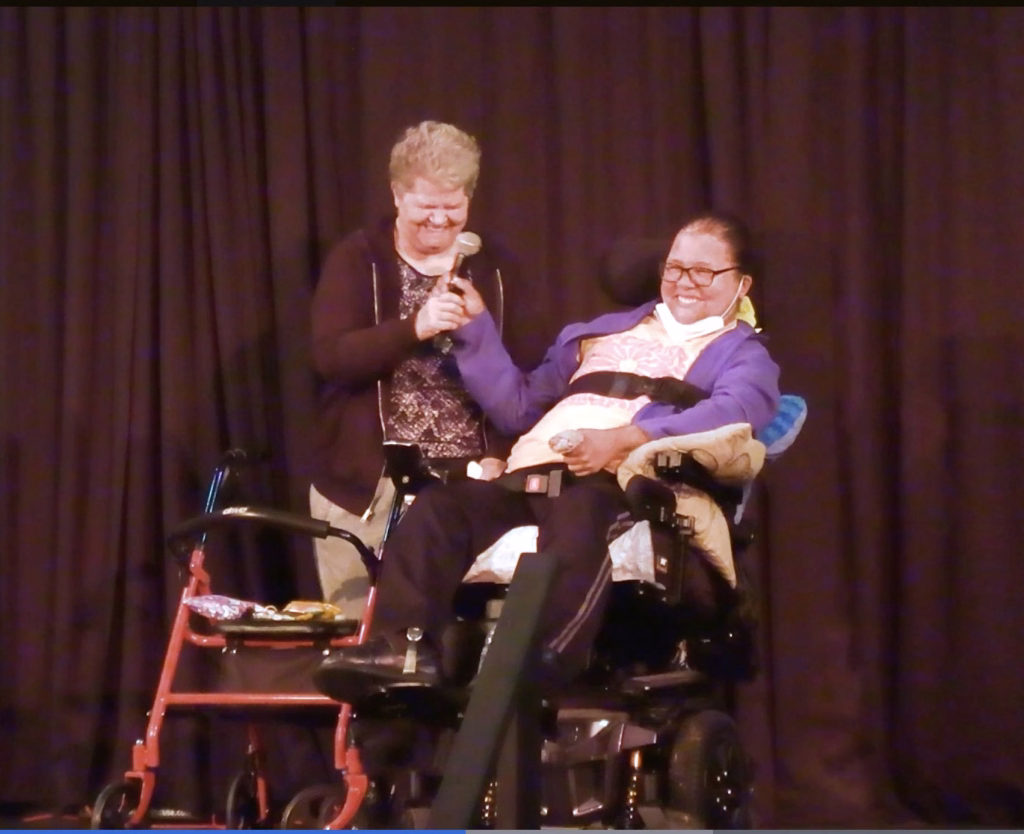 Karen and Phoebe on stage at the Rotunda singing into a microphone.